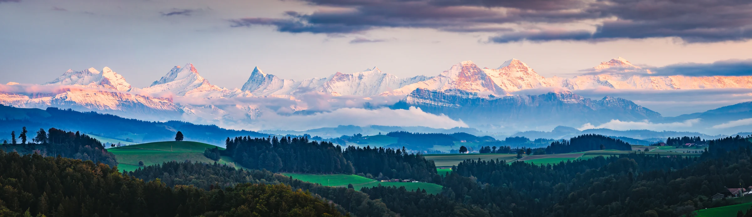 Panoramaansicht Emmental mit Alpenglühen auf Eiger, Mönch und Jungfrau bei Sonnenuntergang, dunstiger Herbstabend, Kanton Bern Schweiz