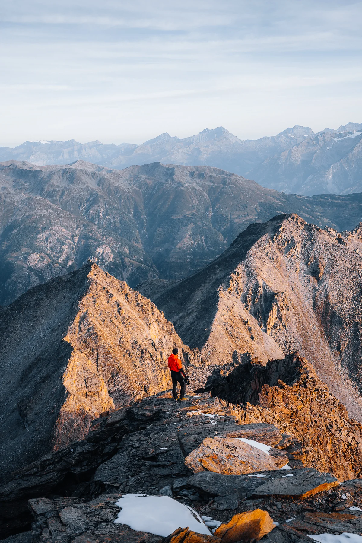 Bergsteiger in roter Jacke auf dem Gipfel des Gross Bigerhorn mit Blick auf die Walliser Alpenkette bei goldenem...