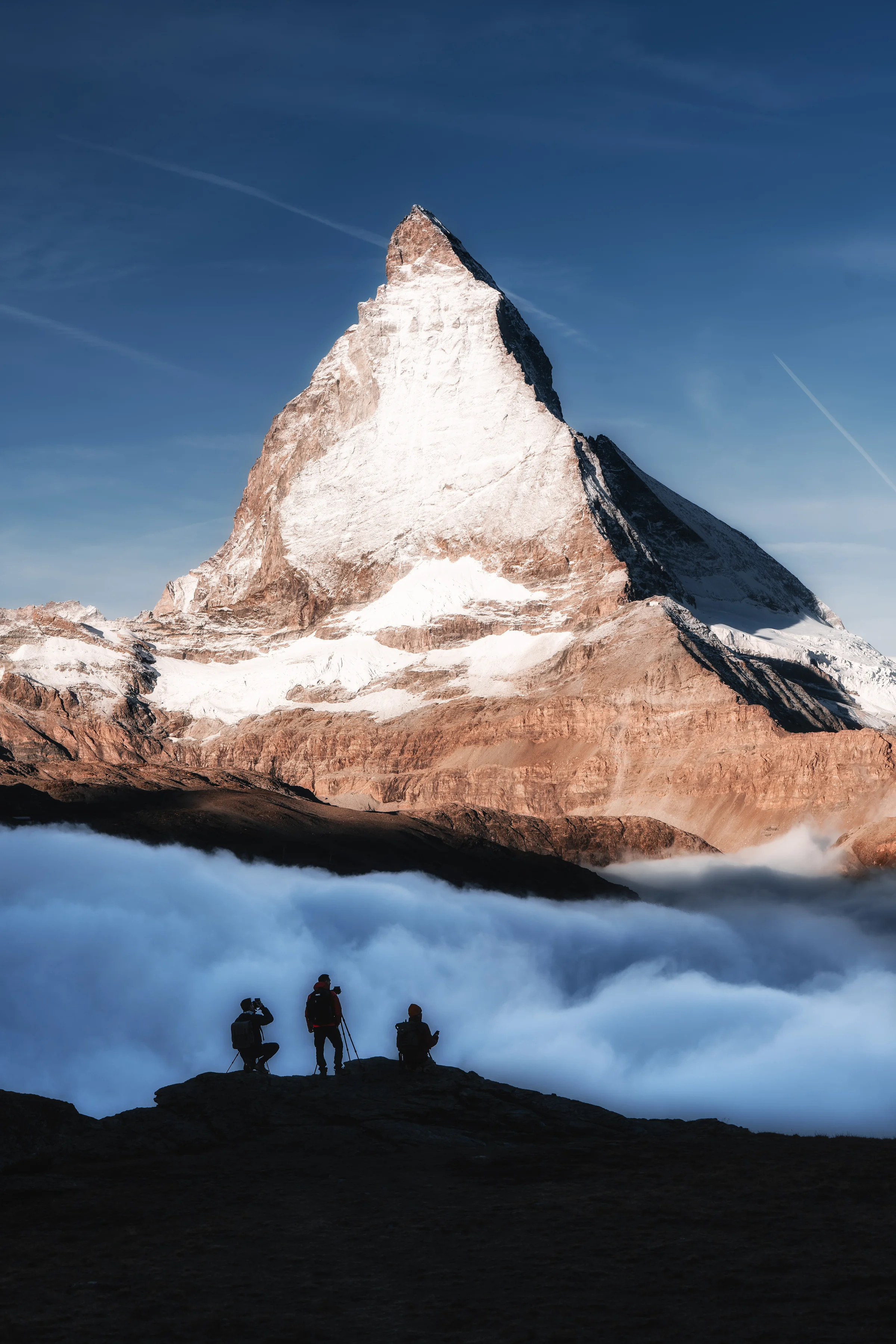 Das Matterhorn erhebt sich majestätisch über einem dichten Nebelmeer mit Silhouetten von Fotografen im Vordergrund,...