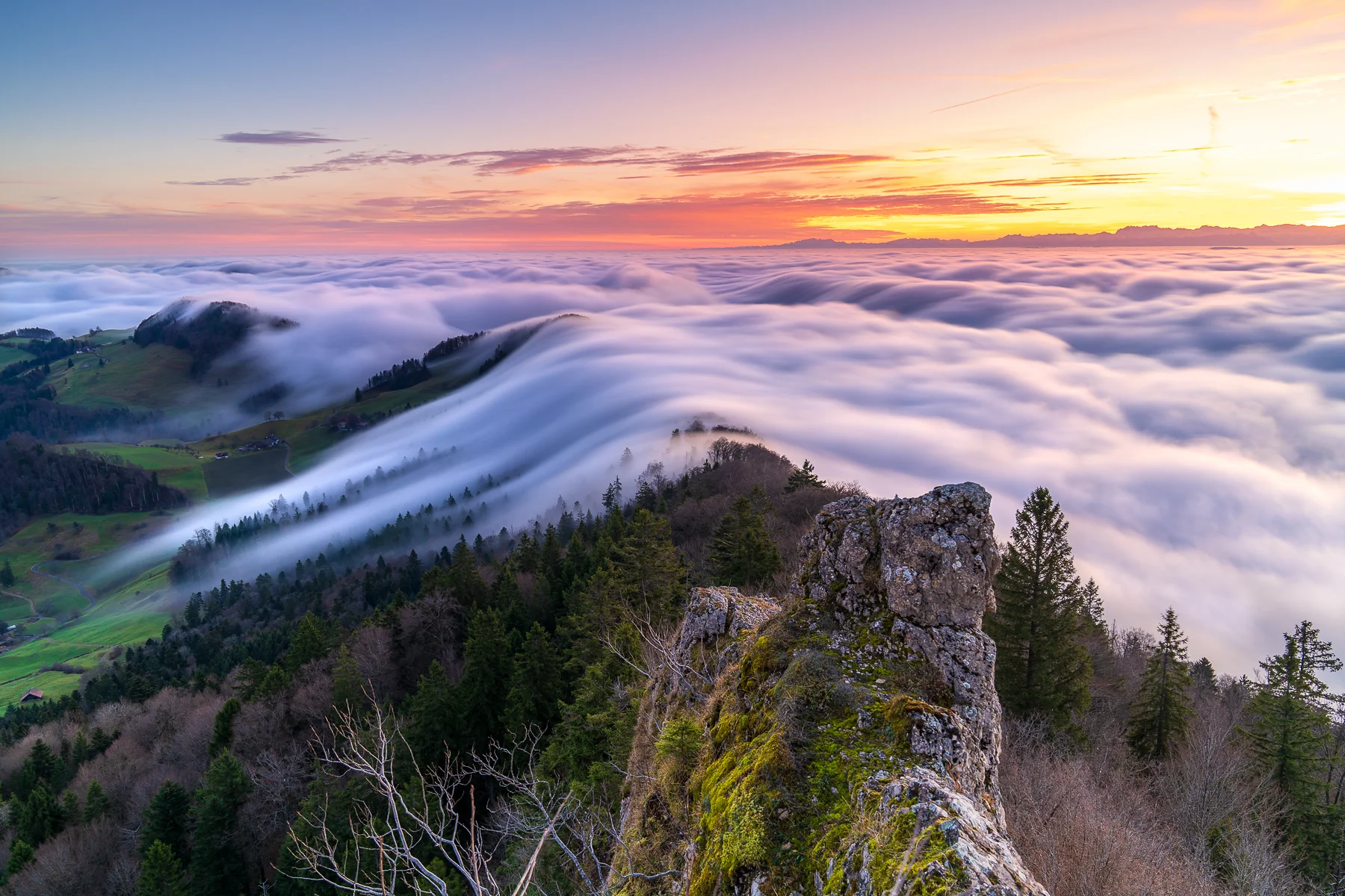 Dramatisches Nebelmeer bei Sonnenaufgang über Baselland mit Felsenvorsprung und Alpenpanorama